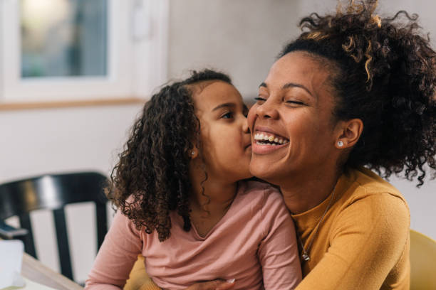 A young girl kissing her mother's cheek.